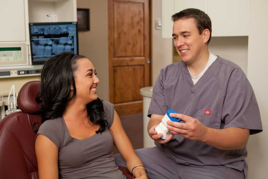 Dentist reviewing digital X-rays on-screen with a smiling patient chairside